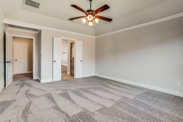 unfurnished bedroom featuring ensuite bathroom, ornamental molding, light colored carpet, ceiling fan, and a tray ceiling