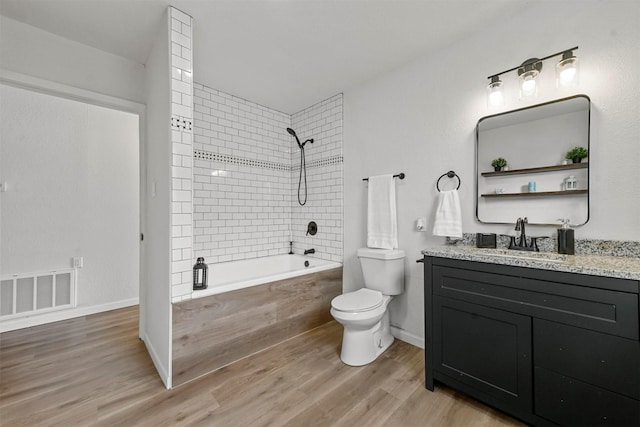 full bathroom with vanity, tiled shower / bath, hardwood / wood-style flooring, and toilet