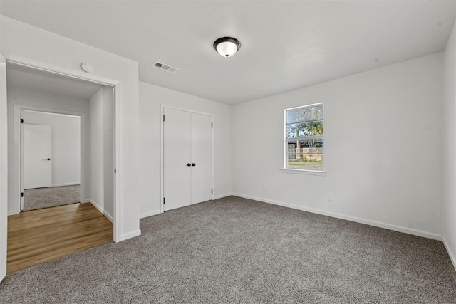 unfurnished bedroom with carpet, visible vents, and baseboards