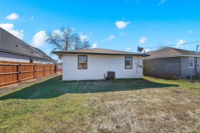 back of property featuring central air condition unit, a fenced backyard, and a lawn