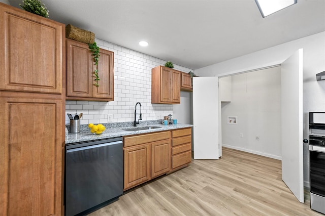 kitchen featuring a sink, light wood-style floors, decorative backsplash, light stone countertops, and dishwasher