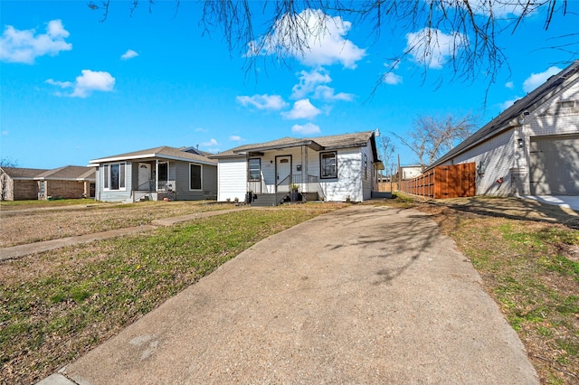 ranch-style home featuring a garage, covered porch, and a front yard