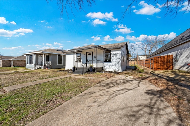 view of front of home with a porch, a front yard, and fence