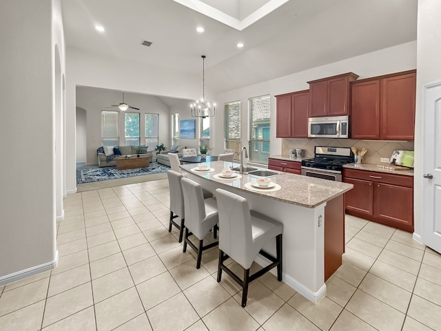 kitchen featuring appliances with stainless steel finishes, sink, a breakfast bar area, backsplash, and a center island with sink