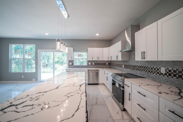 kitchen with stainless steel appliances, white cabinetry, light stone counters, and wall chimney exhaust hood