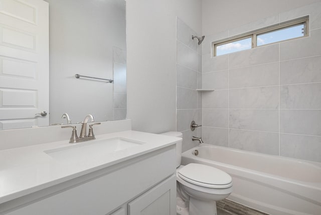 full bathroom featuring vanity, wood-type flooring, tiled shower / bath combo, and toilet