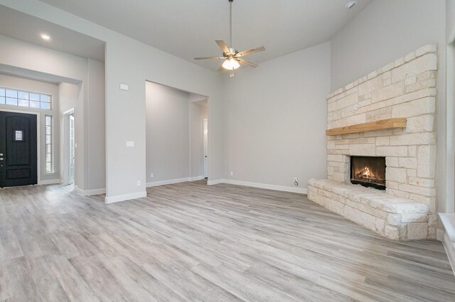 unfurnished living room featuring light hardwood / wood-style flooring, a fireplace, ceiling fan, and a high ceiling