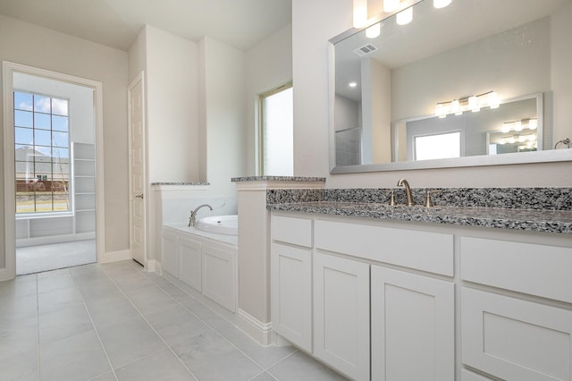 bathroom featuring tile patterned flooring, vanity, and a relaxing tiled tub