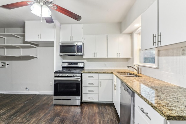 kitchen with appliances with stainless steel finishes, light stone counters, sink, dark hardwood / wood-style floors, and white cabinetry