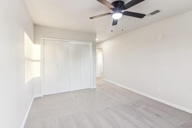 unfurnished bedroom with ceiling fan, a closet, and light carpet