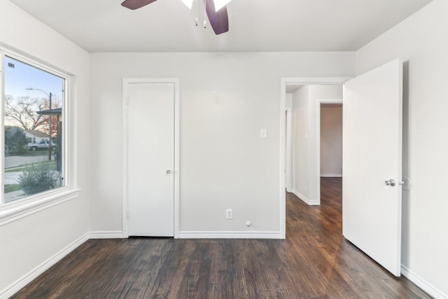 unfurnished bedroom with multiple windows, ceiling fan, and dark wood-type flooring