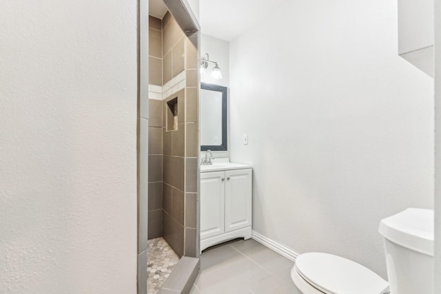 bathroom with tile patterned floors, vanity, toilet, and a tile shower