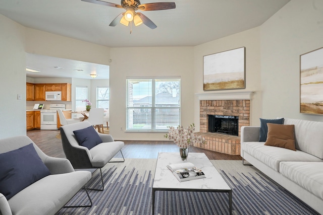 living room with wood-type flooring, ceiling fan, and a fireplace