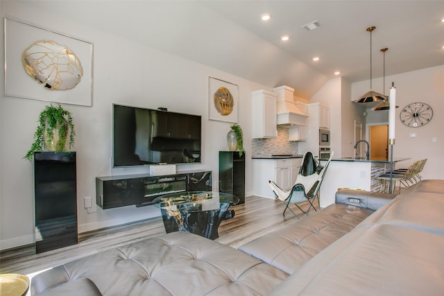 living room with light hardwood / wood-style flooring, lofted ceiling, and sink