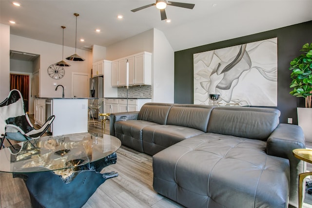 living room featuring ceiling fan, sink, and light hardwood / wood-style flooring