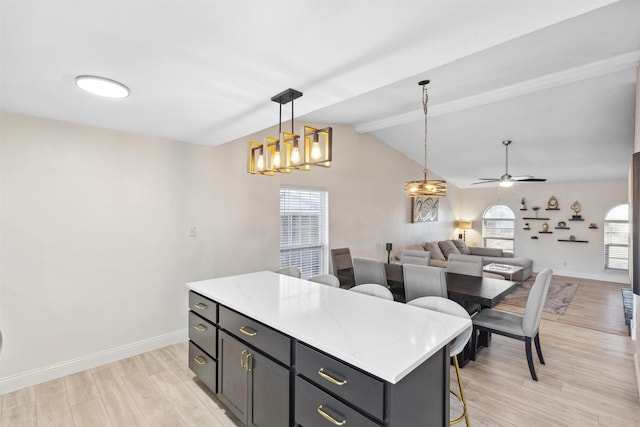 kitchen featuring ceiling fan, a center island, light hardwood / wood-style floors, hanging light fixtures, and a breakfast bar area