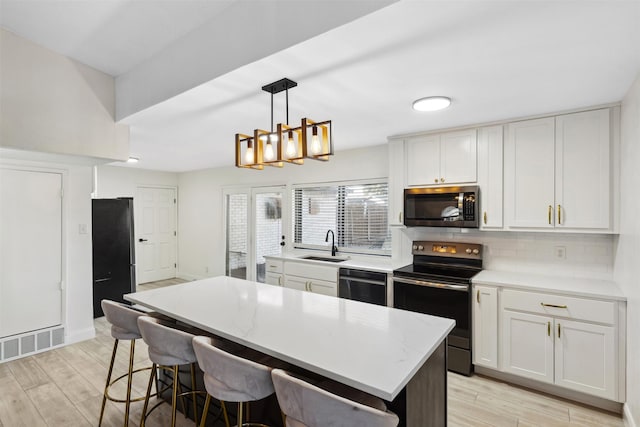 kitchen featuring appliances with stainless steel finishes, sink, decorative light fixtures, white cabinets, and a kitchen island