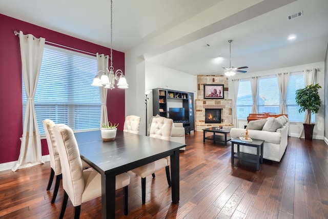 dining space with a fireplace, dark wood-type flooring, and ceiling fan with notable chandelier