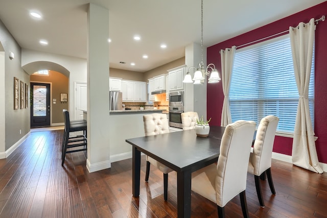 dining space featuring dark wood-type flooring and an inviting chandelier