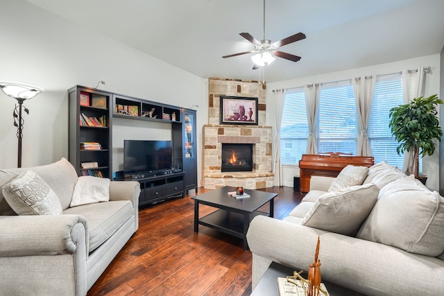 living room featuring dark hardwood / wood-style floors, a stone fireplace, and ceiling fan