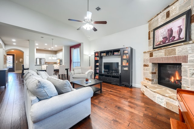 living room featuring dark wood-type flooring, vaulted ceiling, ceiling fan, a fireplace, and plenty of natural light