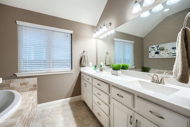 bathroom featuring tile patterned flooring, vanity, tiled bath, and lofted ceiling