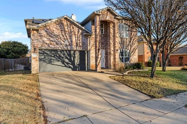 front facade featuring solar panels, a garage, and a front yard