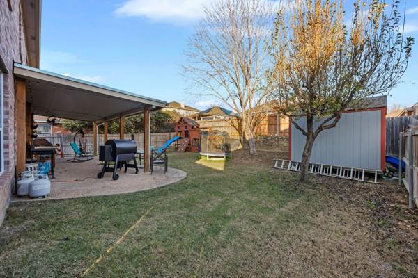 view of yard with a playground, a storage unit, and a patio area