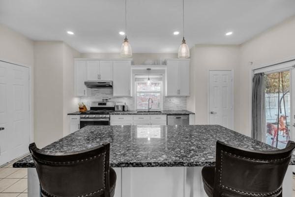 kitchen with white cabinets, stainless steel stove, and a kitchen island