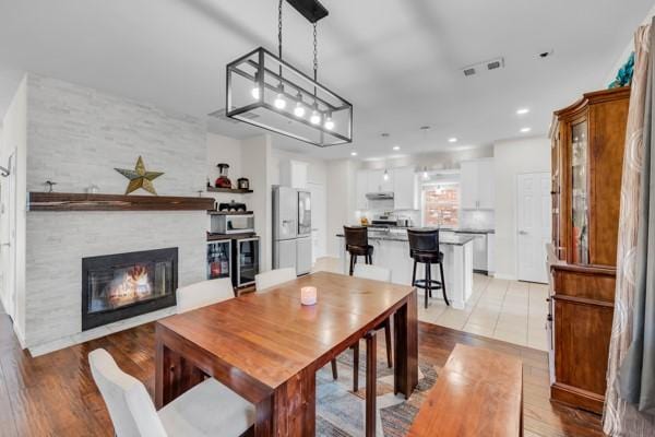 dining area with a fireplace, light wood-type flooring, and beverage cooler