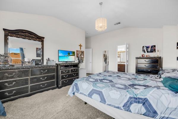 bedroom featuring carpet flooring, a notable chandelier, and vaulted ceiling