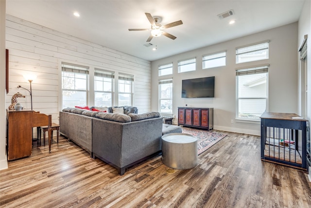 living room featuring ceiling fan, wooden walls, and hardwood / wood-style floors