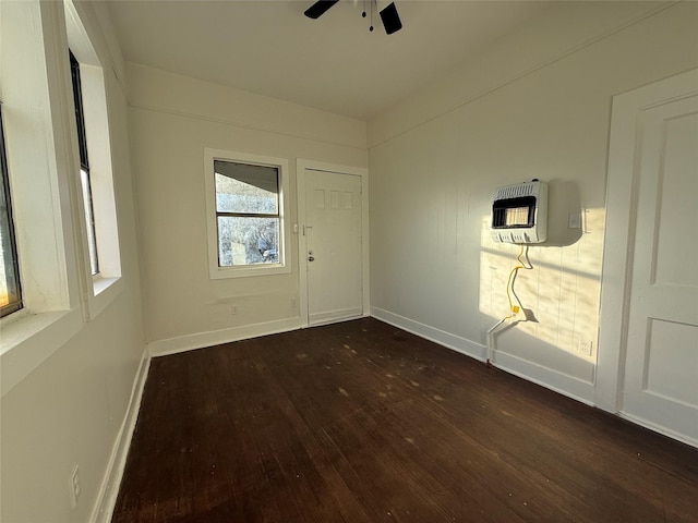 spare room with heating unit, dark wood-type flooring, and ceiling fan