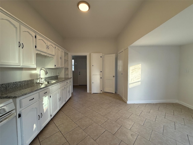 kitchen with dark stone countertops, sink, white electric range, and white cabinets