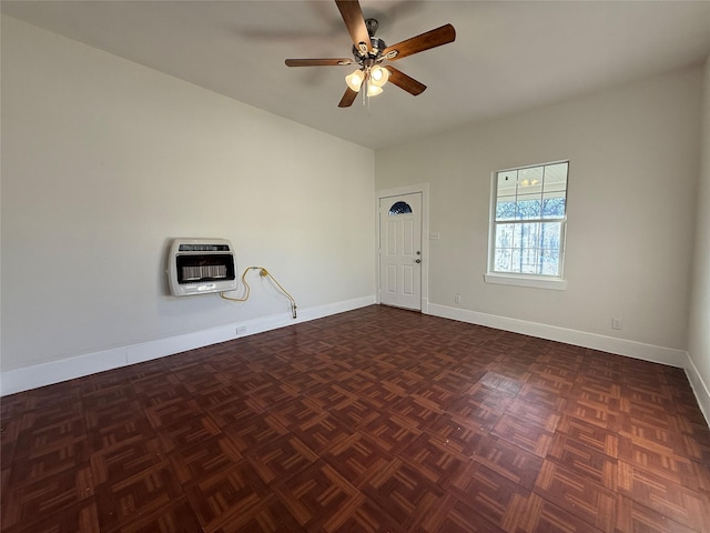 unfurnished room with ceiling fan, dark parquet flooring, and heating unit