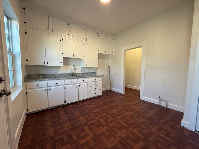 kitchen with plenty of natural light, sink, white cabinets, and dark parquet floors