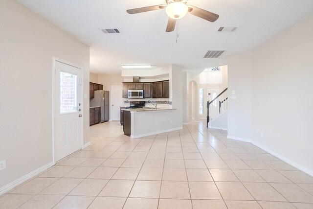 kitchen with kitchen peninsula, decorative backsplash, stainless steel appliances, ceiling fan, and light tile patterned floors