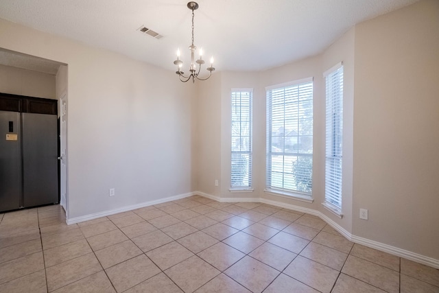 tiled empty room featuring a chandelier