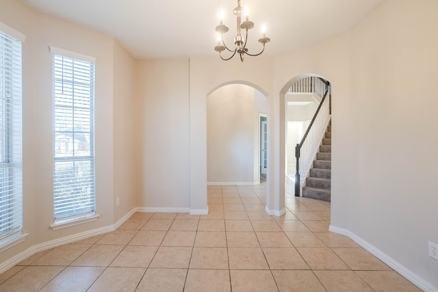 tiled spare room with a chandelier