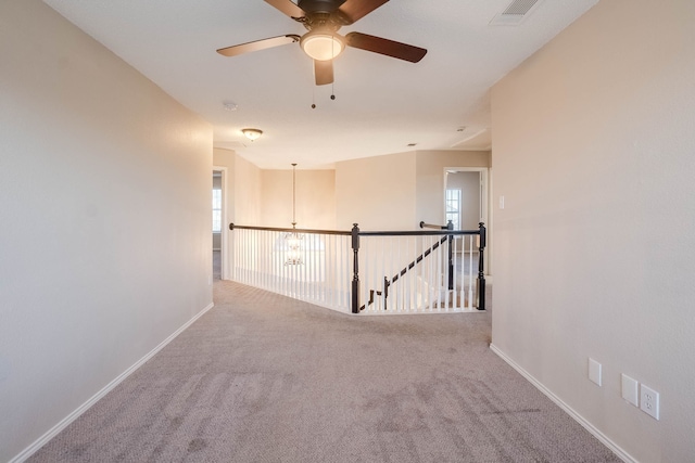 carpeted empty room with ceiling fan with notable chandelier and a healthy amount of sunlight