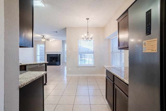 kitchen with dark brown cabinets, light stone countertops, hanging light fixtures, and light tile patterned floors