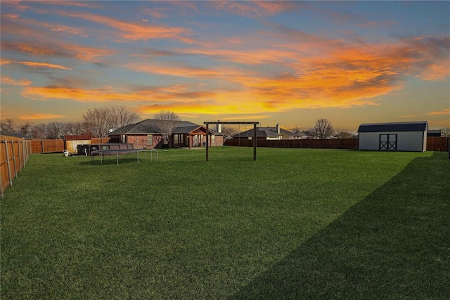 yard at dusk with a shed and a trampoline