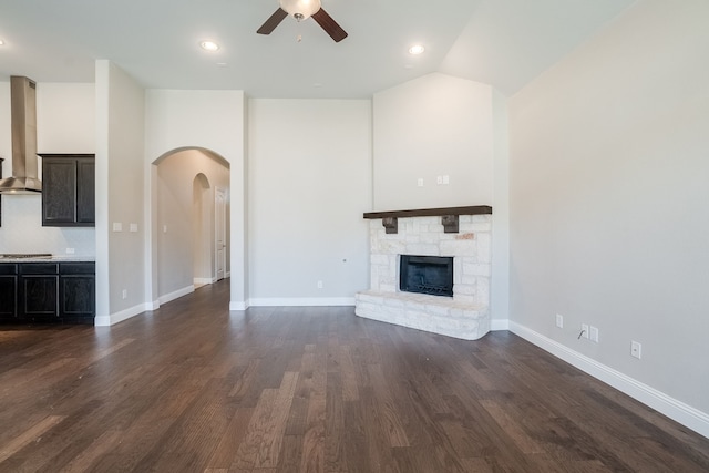 unfurnished living room featuring a fireplace, dark hardwood / wood-style flooring, and ceiling fan