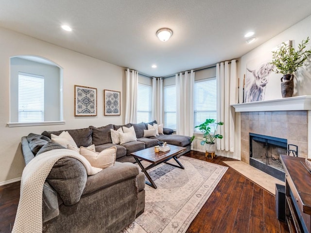 living room with a fireplace, plenty of natural light, and dark hardwood / wood-style floors