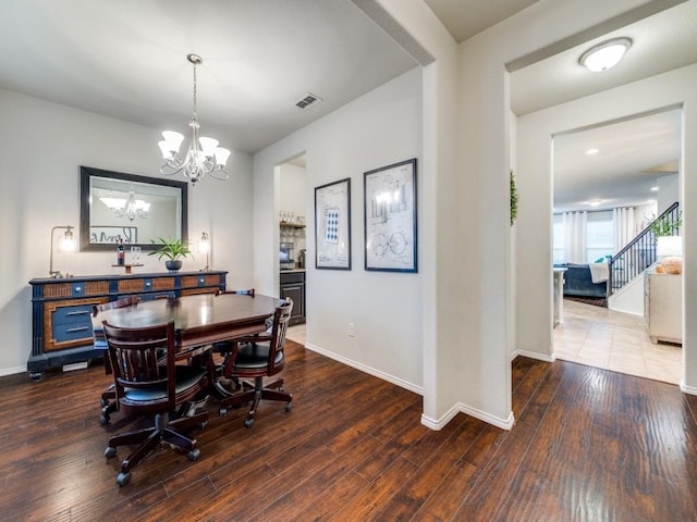 dining area featuring dark wood-type flooring and an inviting chandelier