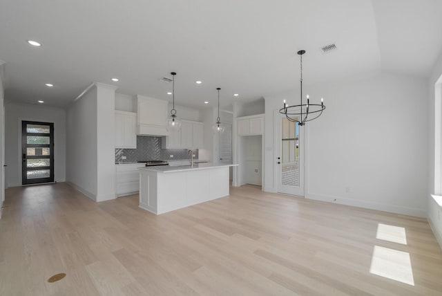 kitchen featuring pendant lighting, sink, a kitchen island with sink, light hardwood / wood-style floors, and white cabinets