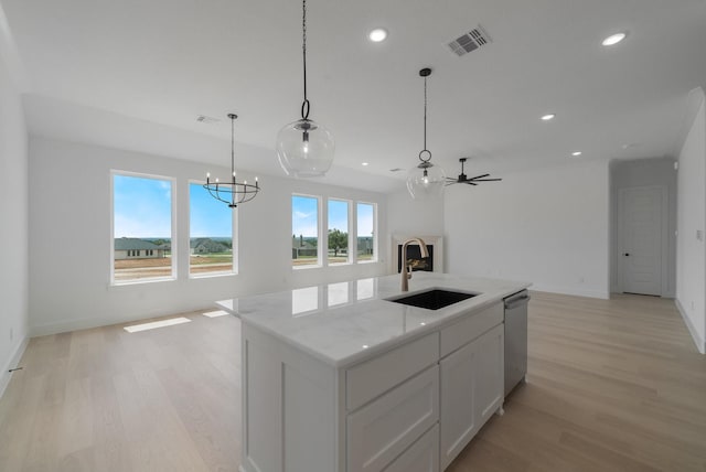 kitchen with sink, white cabinetry, decorative light fixtures, a center island with sink, and stainless steel dishwasher