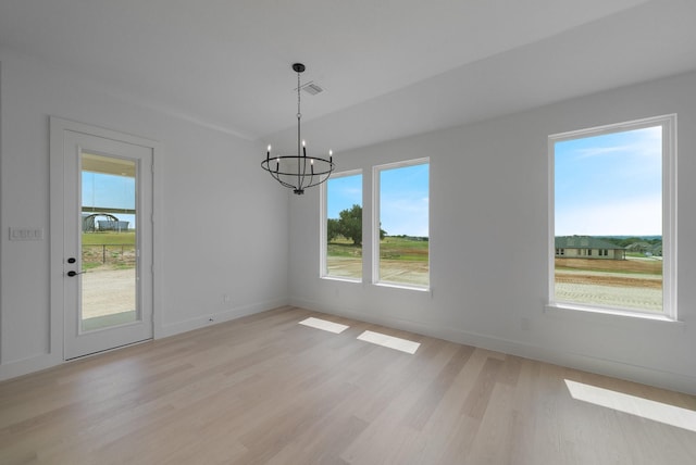 unfurnished dining area featuring a notable chandelier and light wood-type flooring