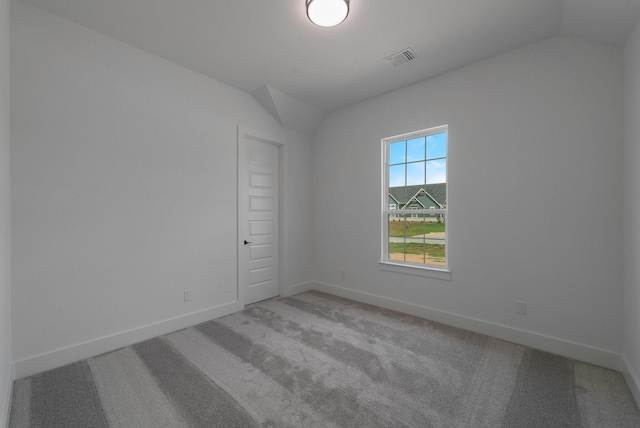 carpeted empty room featuring lofted ceiling