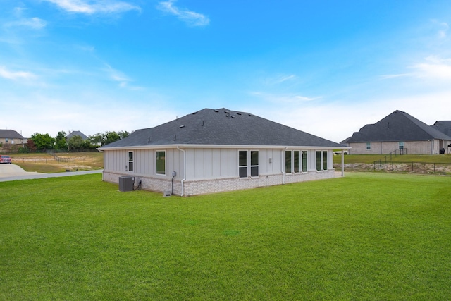 rear view of house featuring a yard and central AC